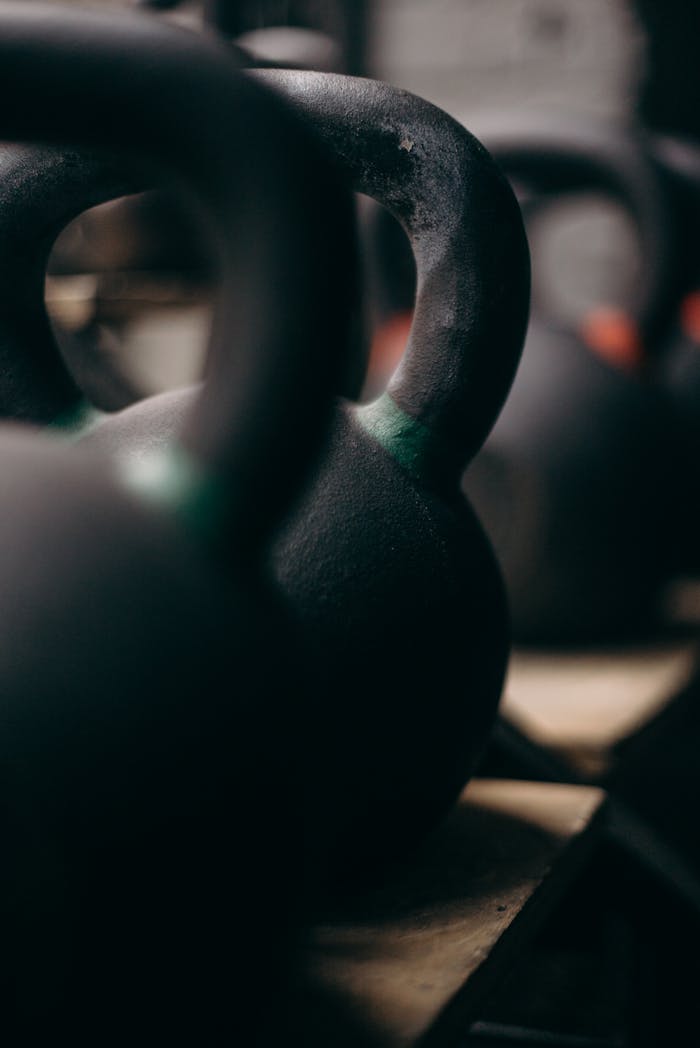 contact-img-01 Detailed view of kettlebells lined up in a gym setting, capturing their rugged texture.