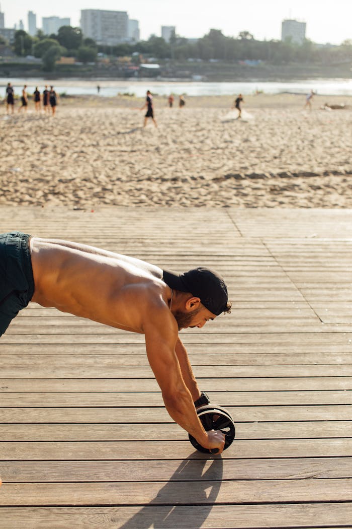 services-img-01 A muscular man works out with an ab roller on a sunny beach boardwalk.
