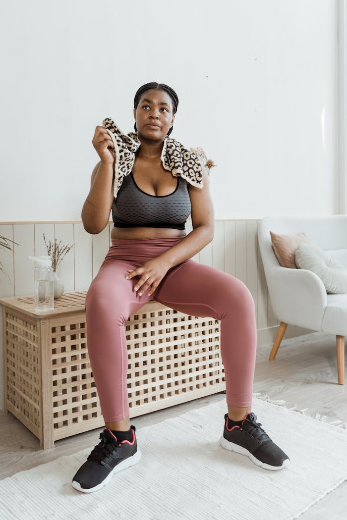 services-04 Young woman in sportswear sitting indoors, embodying fitness and style with a relaxed expression.
