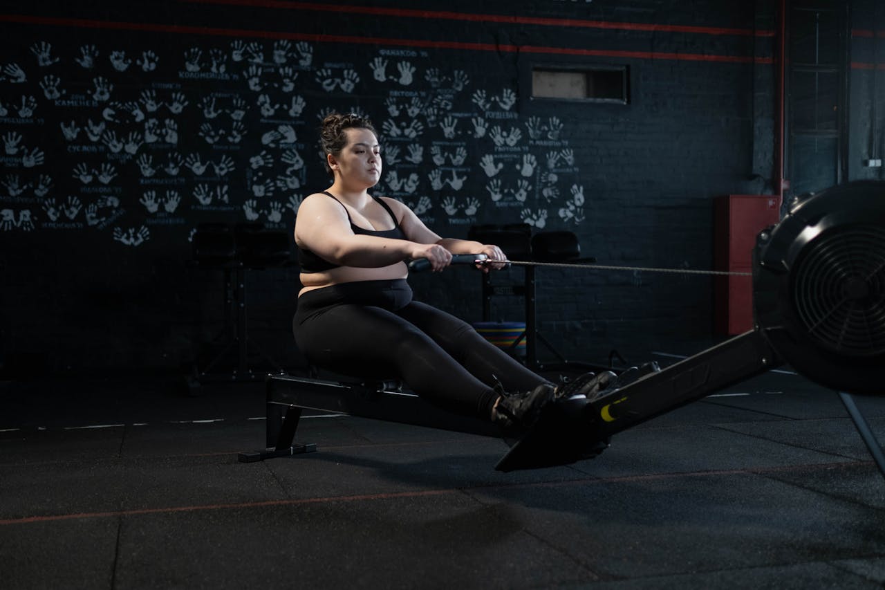 services-03 Plus-size woman working out on a rowing machine indoors, embracing fitness and a healthy lifestyle.